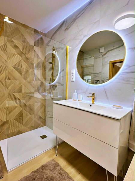 A bathroom with a wood-patterned floor and a stylish shower in a 3-room apartment.