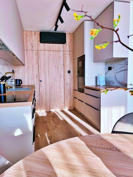 A kitchen in a 3-room apartment with a wooden decor and built-in appliances.