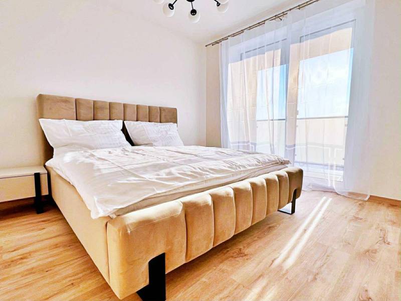 A bedroom in a 3-room apartment with a light bed and a floor with a wooden decor.