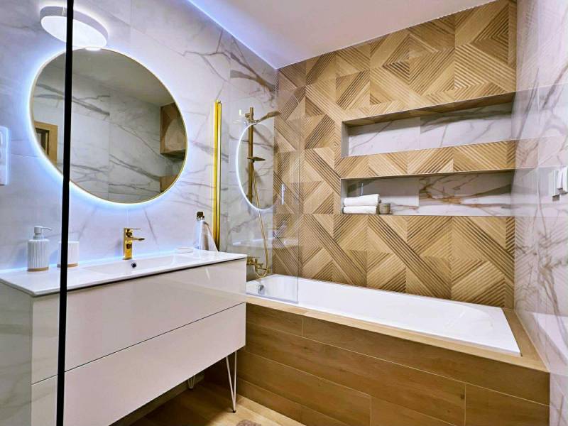 Bathroom with wood-patterned flooring, mirror, and shower in a 3-room apartment.