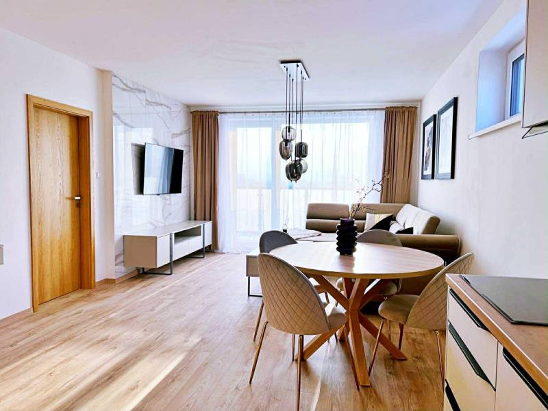 Living room in a three-room apartment with light furniture and a wooden decor floor.