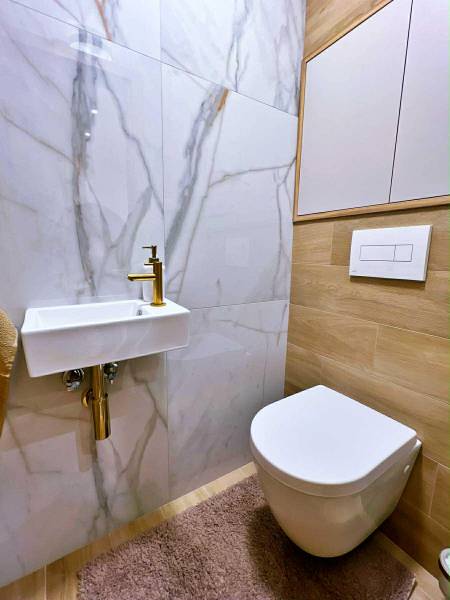 Bathroom with ceramic sink, mirror, and floor with wooden decor in a 3-room apartment.