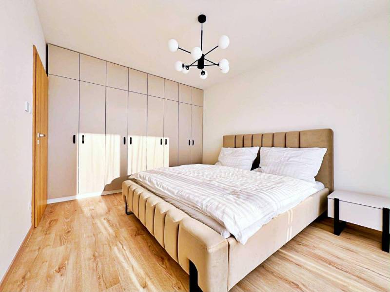 Bedroom in a 3-room apartment with a bed, built-in wardrobe, and wooden decor flooring.