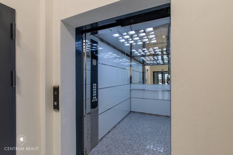 Interior of an elevator with stainless steel panels and a mirror, visible buttons.