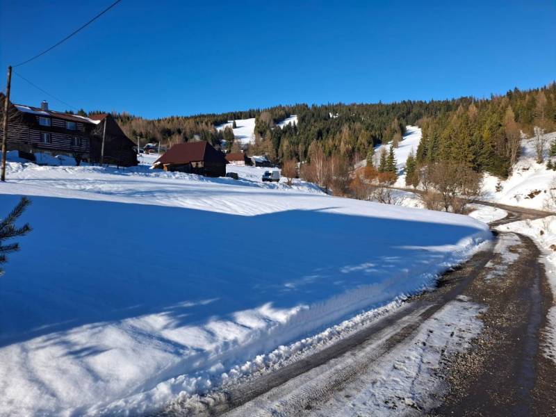Snow-covered residential lands in Ždiar, set in a mountainous landscape with wooden cottages.