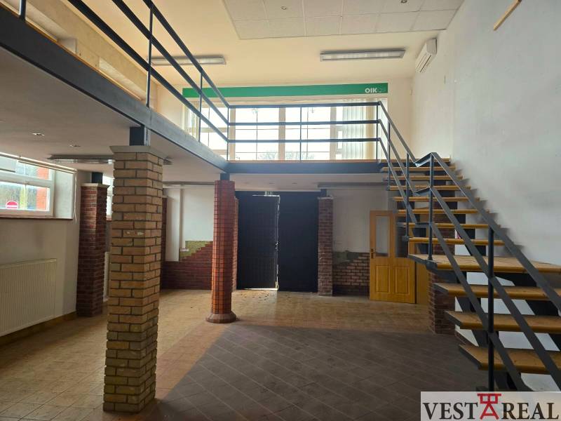 Commercial spaces with wood-patterned flooring and a staircase next to brick pillars.
