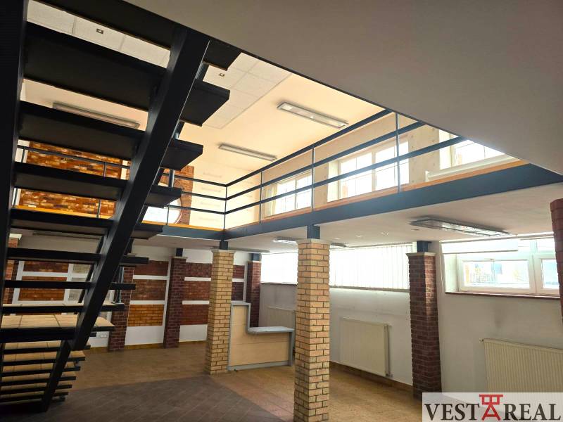 Interior commercial spaces with wood-patterned flooring and metal staircase.