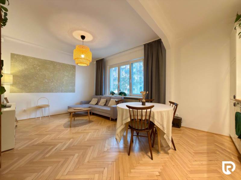 Living room in a two-room apartment with a brown sofa and a wooden decor floor.