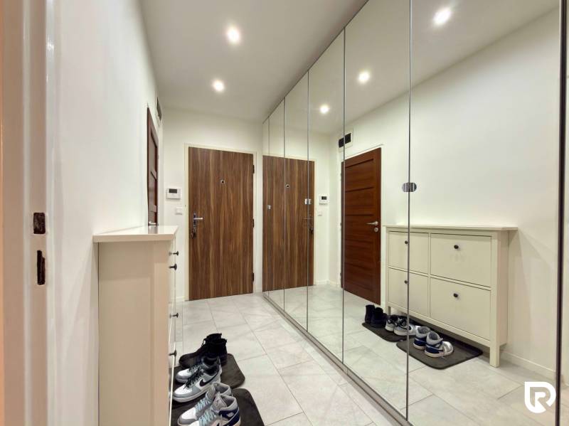 Entrance hall in a 2-room apartment with a shoe cabinet and a mirrored wall, cladding in wood decor.