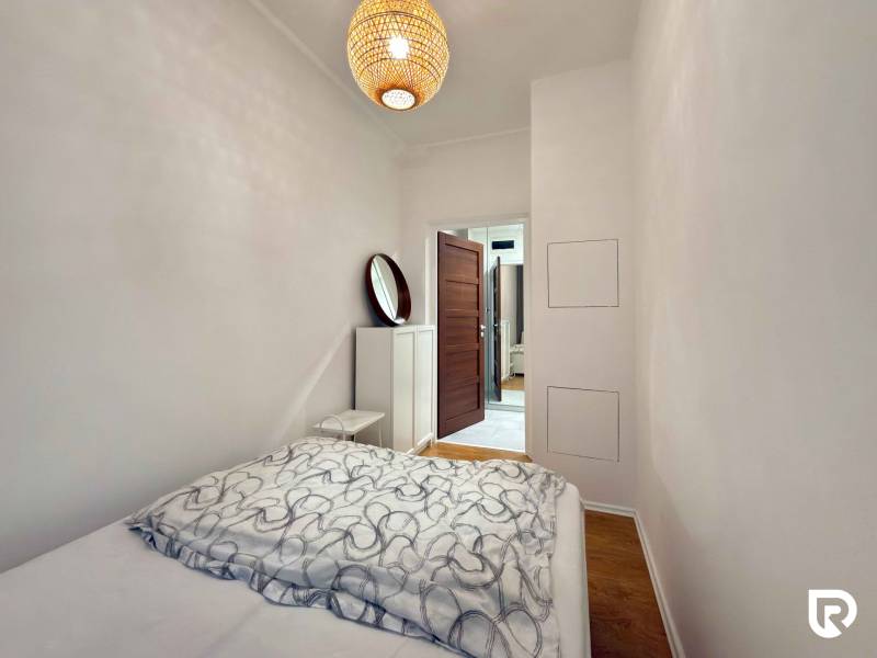 Bedroom with a bed and wooden decor flooring in a two-room apartment.