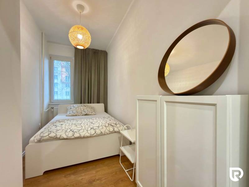 A room with a bed, a mirror, and decorative lighting in a 2-room apartment.