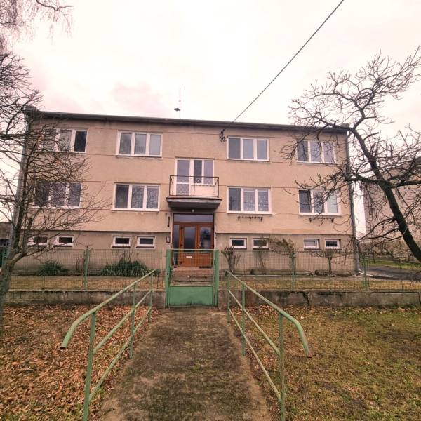 An apartment building in Kuklov with a front garden and a staircase leading to the entrance door.