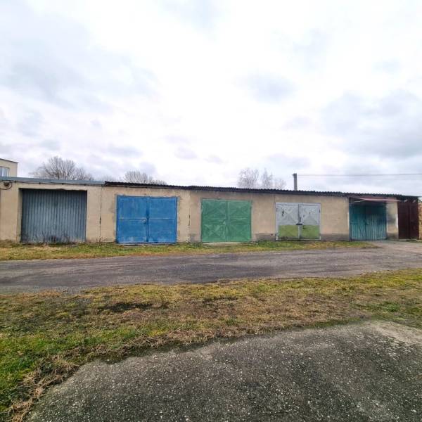 A building with a series of colorful garage doors in Kuklov, next to an asphalt road.