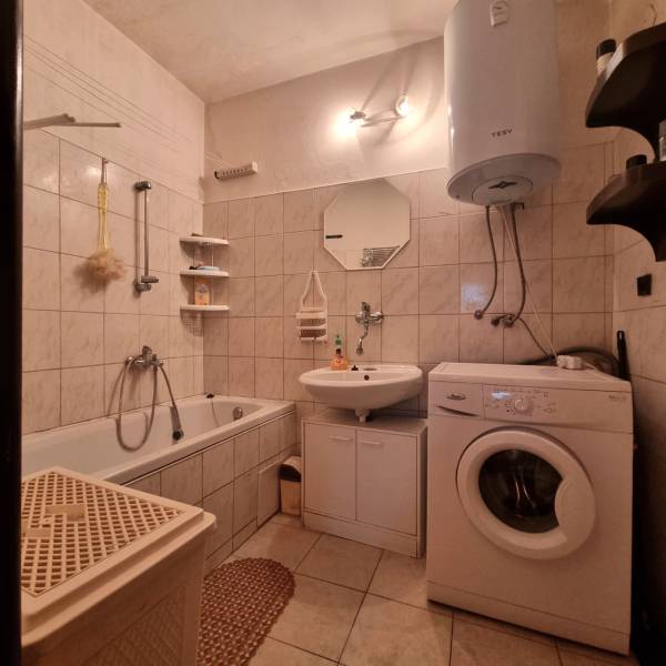 Bathroom in a 3-room apartment with a bathtub, washing machine, and gas water heater.