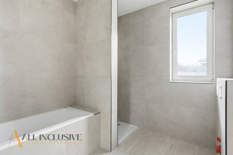 A bathroom in a family house with a bathtub, a shower corner, and a window without curtains.