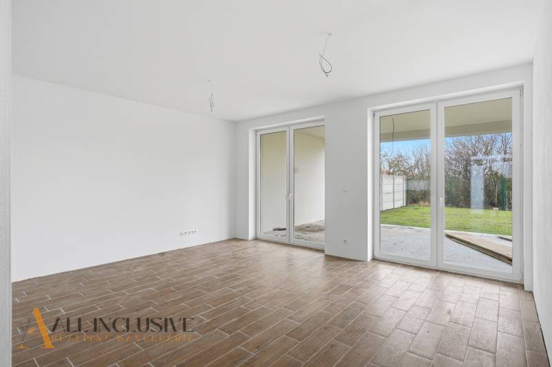 A room in a family house with a wooden decor floor and French windows.