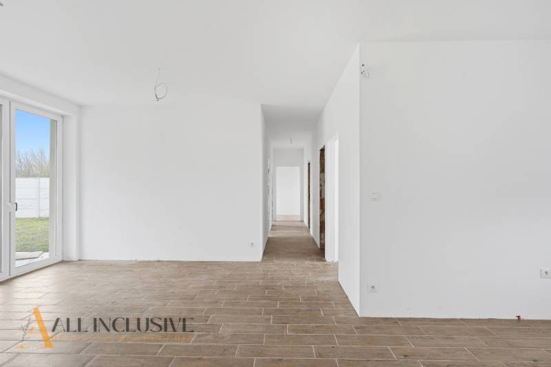 A white hallway in a family house with a wooden decor floor and glass doors to the yard.