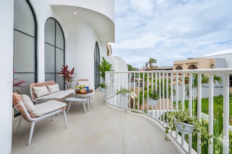 Spacious balcony in a villa with comfortable seating, plants, and a view of Berawa in Canggu.