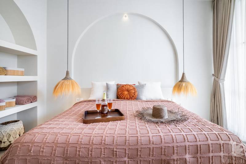 A bedroom in a villa with a comfortable bed, decorative pillows, and hanging lamps.