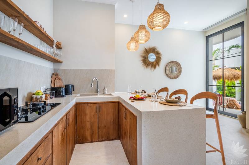 Interior of a villa with a kitchenette, wooden cabinets, and decorative mirrors.