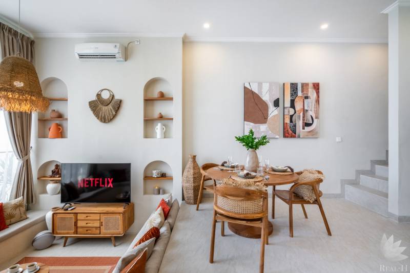 Living room of the villa with a TV, dining table, and decorative elements on the walls.