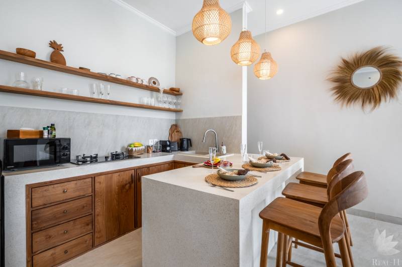 A villa kitchen with stylish wooden elements, bar stools, and pendant lamps.