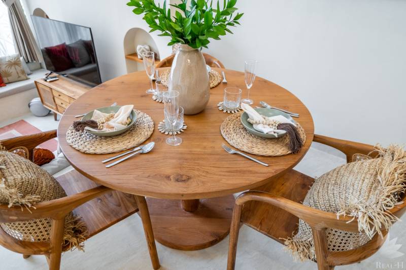 Dining table in a villa with wooden decor, seating and set plates.