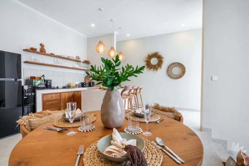 A table set in a villa with a wooden floor decor and a kitchenette.