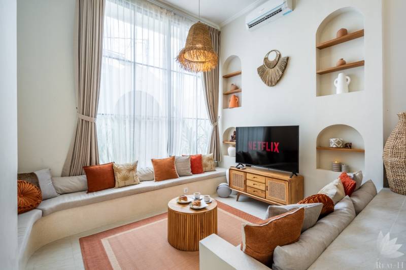 Bright living space in the villa with a sofa, TV, and decorative lighting.