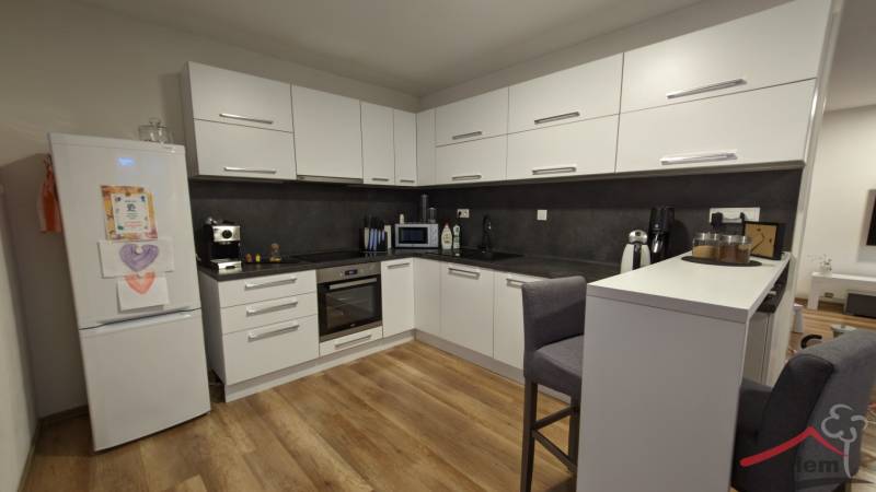 A kitchen in a 2-room apartment with white cabinets and a wood-patterned floor.
