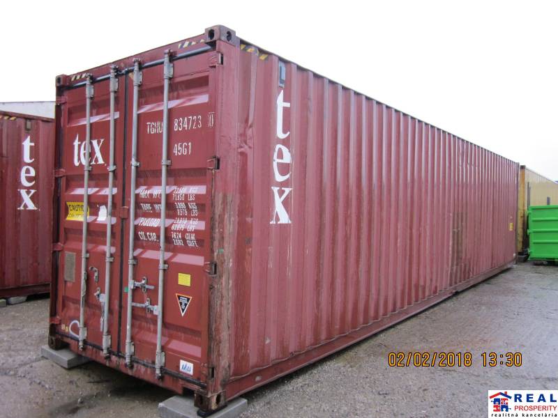 Red shipping container on Strojnícka Street in Prešov near warehouses and halls.