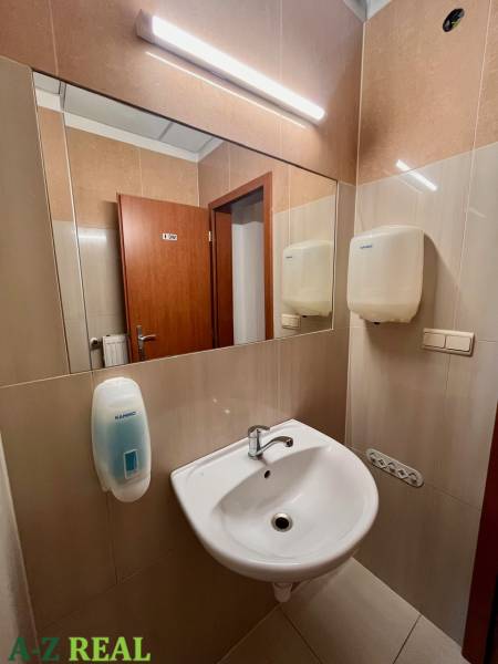 Offices with a sink, mirror, and soap dispenser.