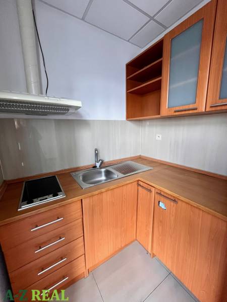 Kitchen unit in offices with a cooktop and cabinets with wooden decor.