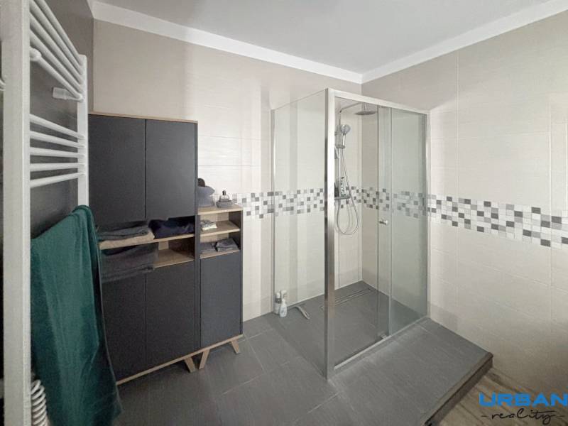 A bathroom in a 3-room apartment with a large shower and storage space.