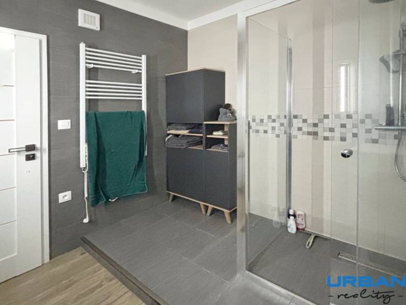 A bathroom with a spacious shower and a ladder radiator in a 3-room apartment.