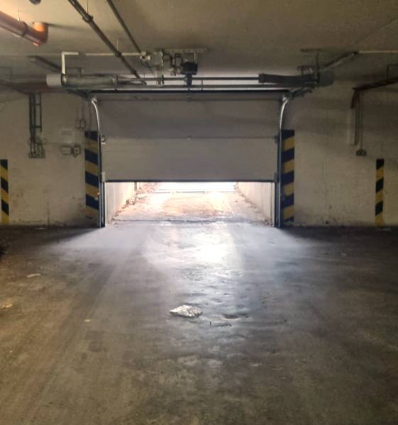 A half-open garage door leads outside, the surroundings are illuminated by indirect light.