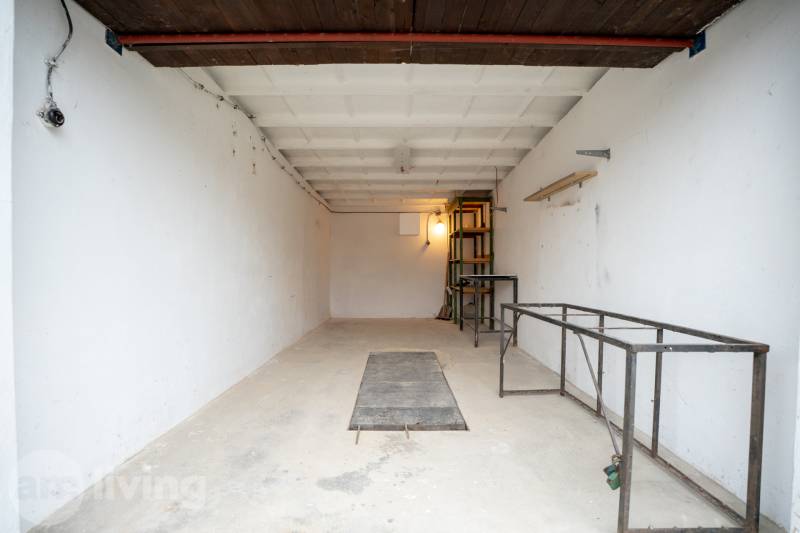 Spacious garage interior with metal shelves and white walls.