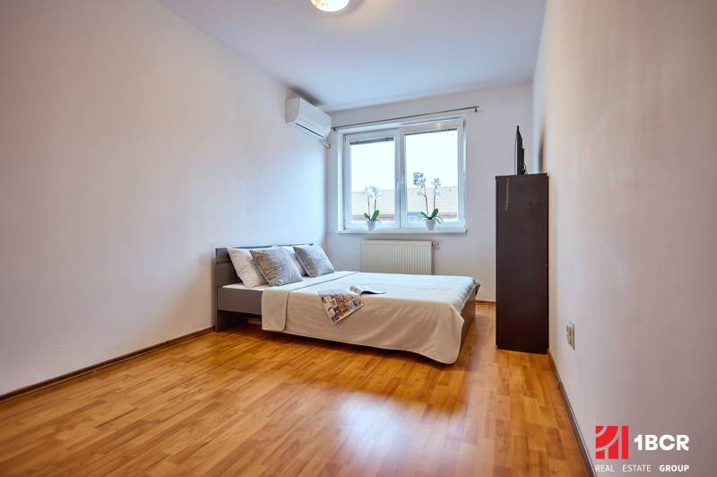A bedroom with a bed, a floor with a wooden decor, in a 2-room apartment.