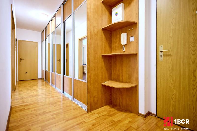 The hallway in a 2-room apartment with a wooden decor floor and built-in cabinets.
