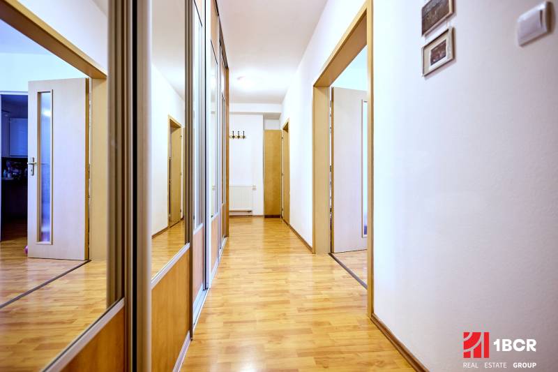 A hallway with a wood-patterned floor and built-in wardrobes in a two-room apartment.
