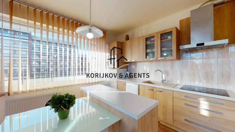 A kitchen with a wooden decor floor in a 2-room apartment, light furnishings, and a large window.