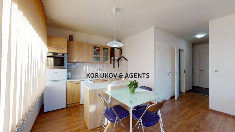 A kitchen in a 2-room apartment with a wood-patterned floor and a table with chairs.