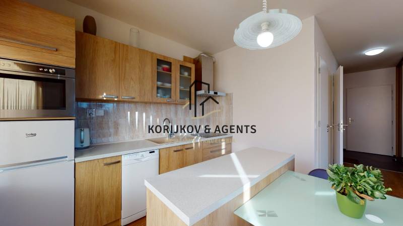 A kitchen in a 2-room apartment with a wooden decor, equipped with appliances and lighting.