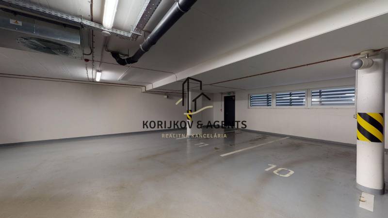 Spacious parking space in the garage marked with number 10, white walls, and ventilation.