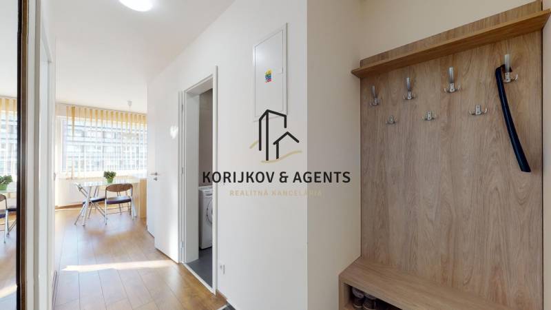 A hallway with a wooden decor floor and a coat rack in a 2-room apartment.