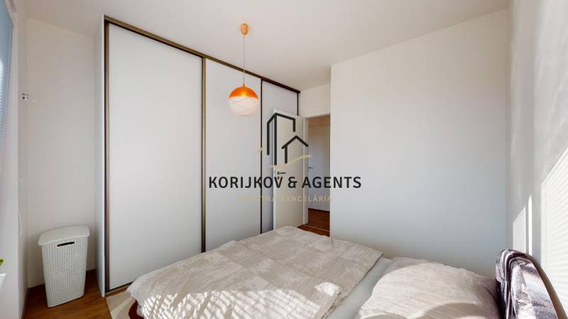 Bedroom in a two-room apartment with a sliding wardrobe and a floor bed with a wooden decor.