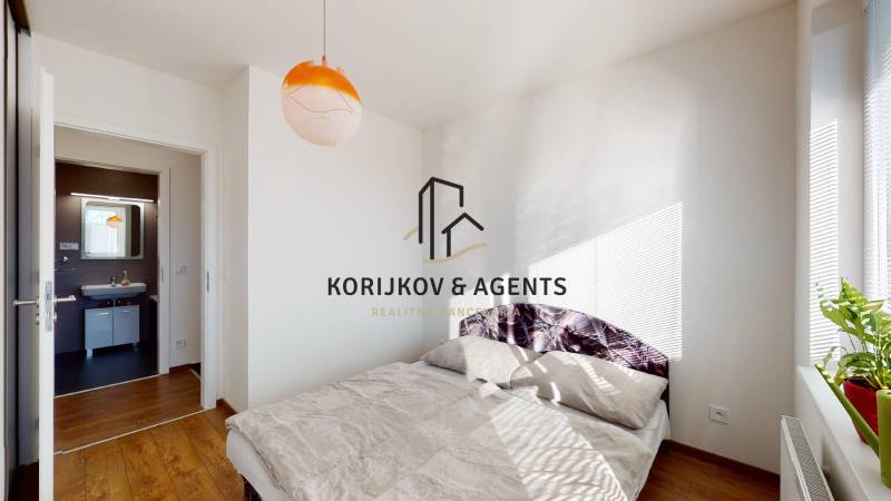Bedroom of a two-room apartment with a bed and a wooden decor floor.