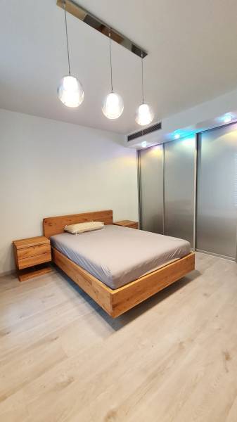 Bedroom with a wooden bed, nightstands, and a floor with a wood decor in a 3-room apartment.