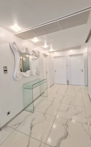 Interior of a 3-room apartment with glossy tiles, a mirror, and a glass table.