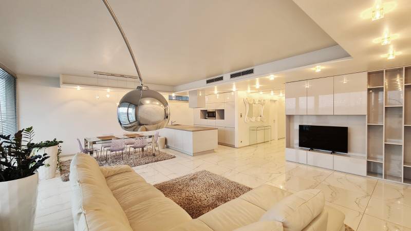 Interior of a 3-room apartment with an open kitchen and a white sofa.